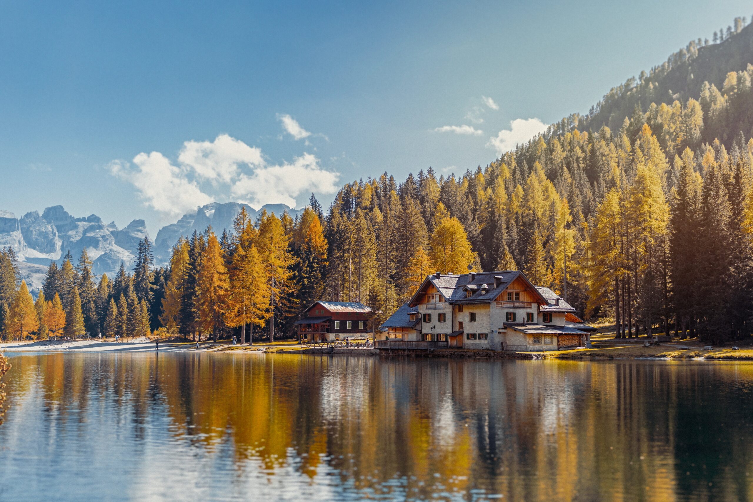 wooden cabin situated right on the lake with autumn-colored trees in the background